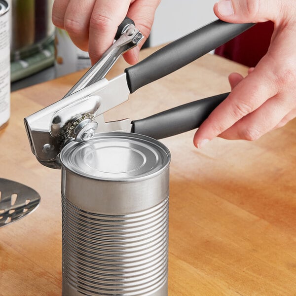 A person using a Swing-A-Way handheld can opener with a black handle to open a can.
