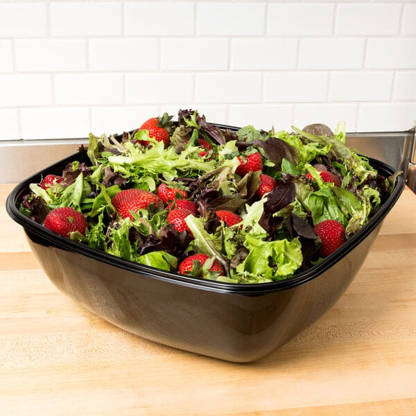 A Sabert black catering bowl filled with salad and strawberries.