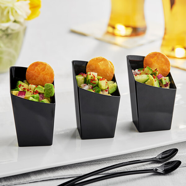 A group of small black cups with food in them.