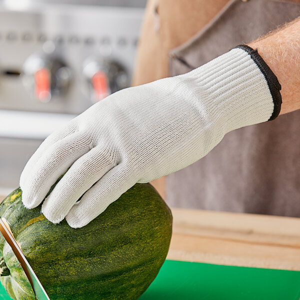 A person wearing Choice Level cut-resistant gloves cutting a watermelon.