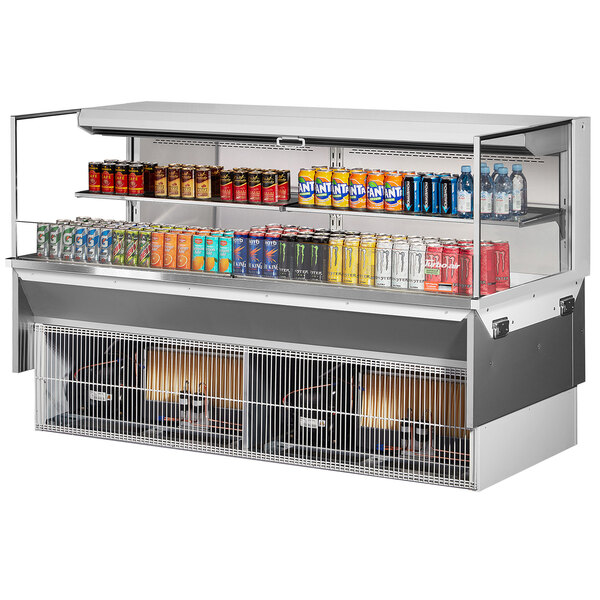 A Turbo Air refrigerated display case with shelves holding cans of soda and an energy drink on a counter.