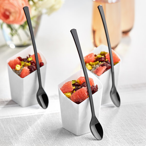 Three small white containers with fruit and Visions black plastic tasting spoons inside.