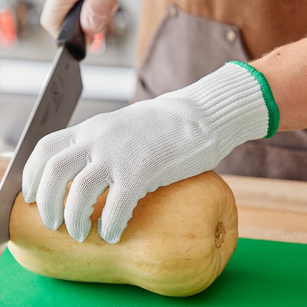 A person using a Choice Level cut-resistant glove to cut a squash with a knife.