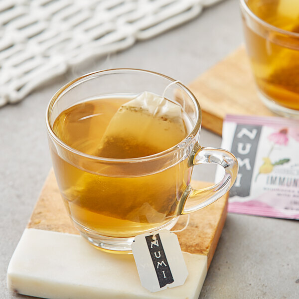 A glass mug of Numi Organic Immune Boost tea with a tea bag in it.