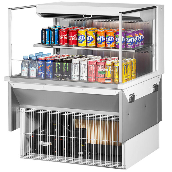 A Turbo Air white drop-in refrigerated display case with cans of soda and energy drinks on shelves.
