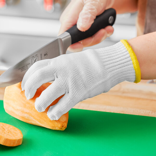 An extra-small Choice Level A6 cut-resistant glove being used to cut a vegetable.