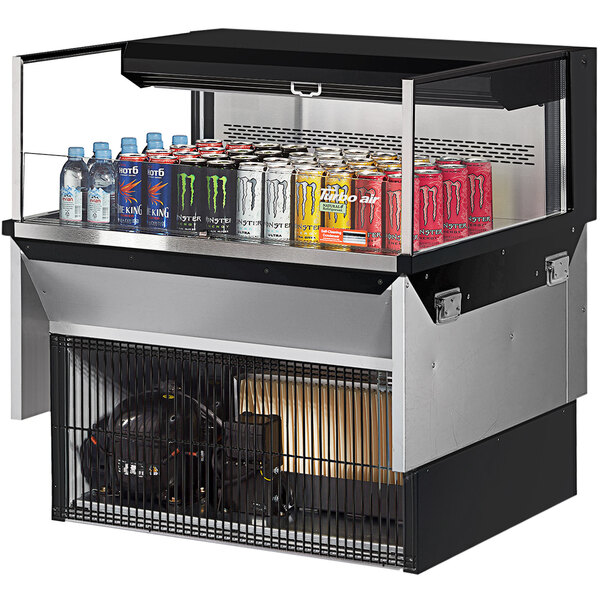 A black Turbo Air refrigerated display case on a counter with cans of soda and other drinks.