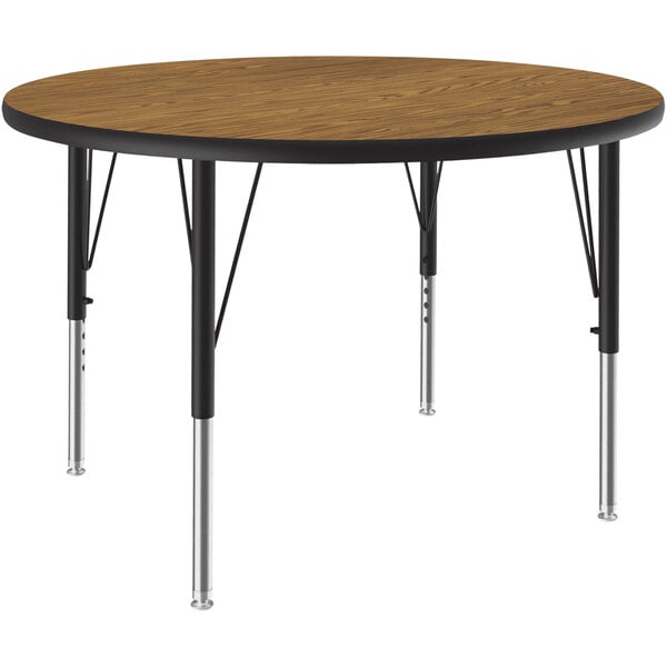 A Correll round activity table with black metal legs and a medium oak top.