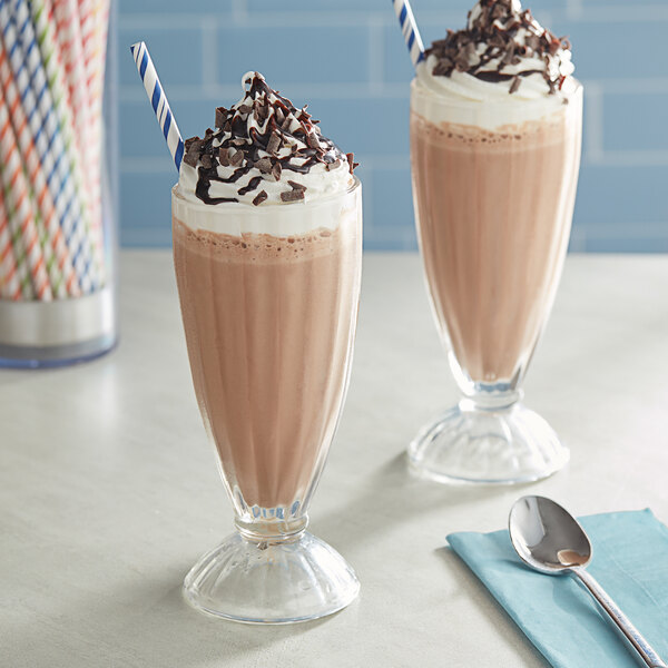 Two glasses of chocolate milkshakes with straws and a spoon.
