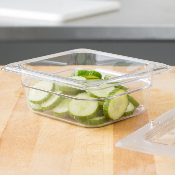 A clear plastic Cambro food pan with cucumber slices inside.