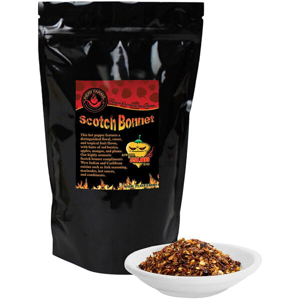 A black bag of Fiery Farms Red Jamaican Scotch Bonnet Pepper Flakes on a counter next to a white bowl of food.