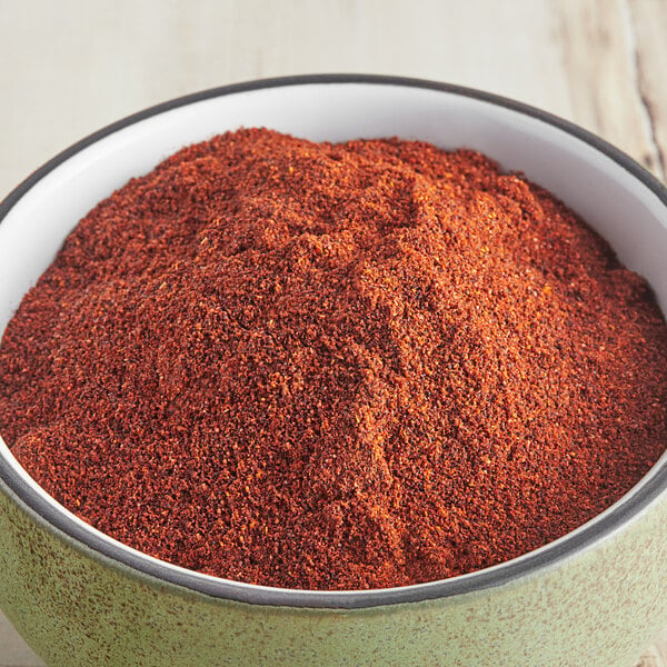 A bowl of McCormick Culinary Ground Chipotle Chile Pepper on a wooden table.