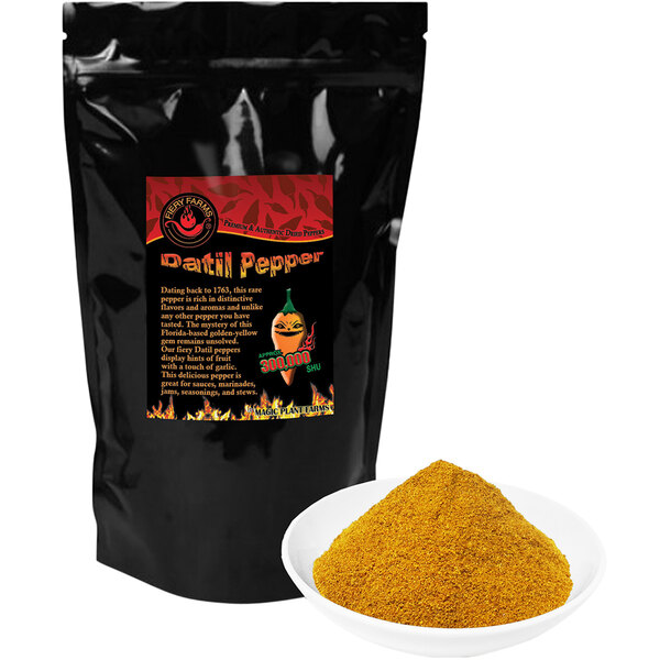 A black bag of Fiery Farms Orange Datil Pepper Powder next to a bowl of yellow powder.