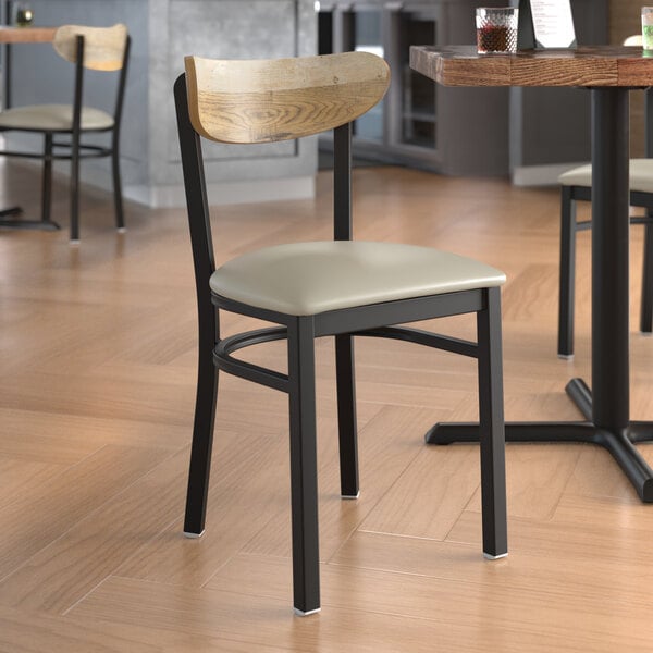 A Lancaster Table & Seating Boomerang chair with a driftwood back and light gray vinyl seat in a restaurant.