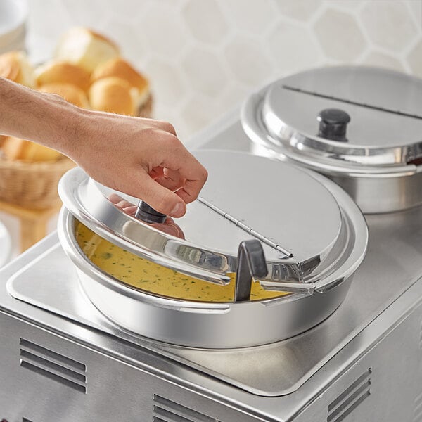 A hand using the hinged lid to cover a stainless steel inset on a counter.