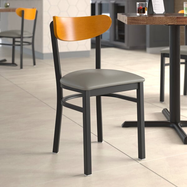 A Lancaster Table & Seating Boomerang Series chair with dark gray vinyl and cherry wood.