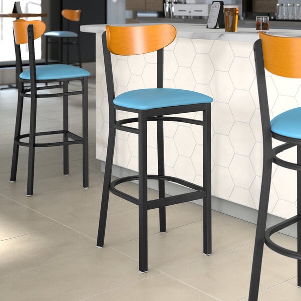 A group of Lancaster Table & Seating Boomerang Series bar stools with blue vinyl seats and cherry wood backs.