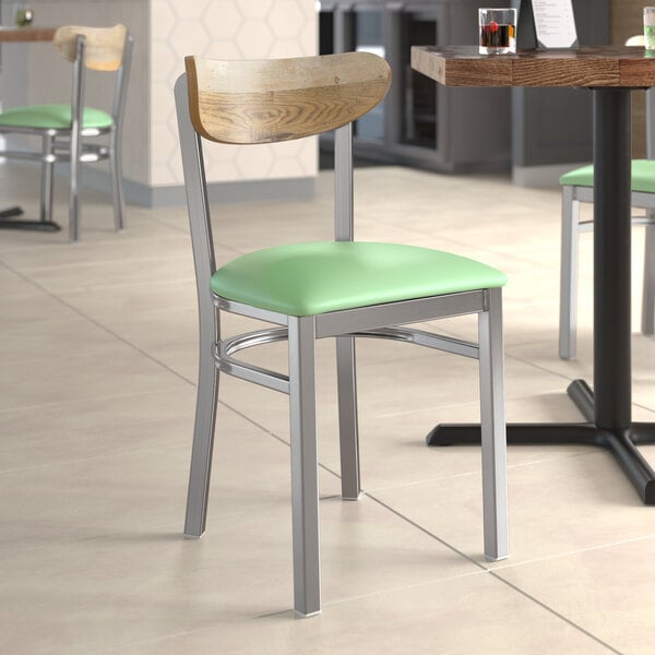 A Lancaster Table & Seating chair with a seafoam vinyl seat in a restaurant.