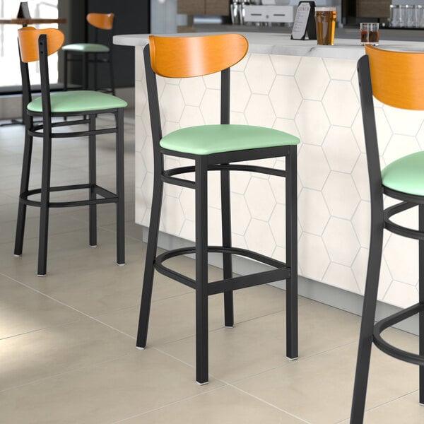 A group of Lancaster Table & Seating bar stools with seafoam vinyl seats and cherry wood backs.