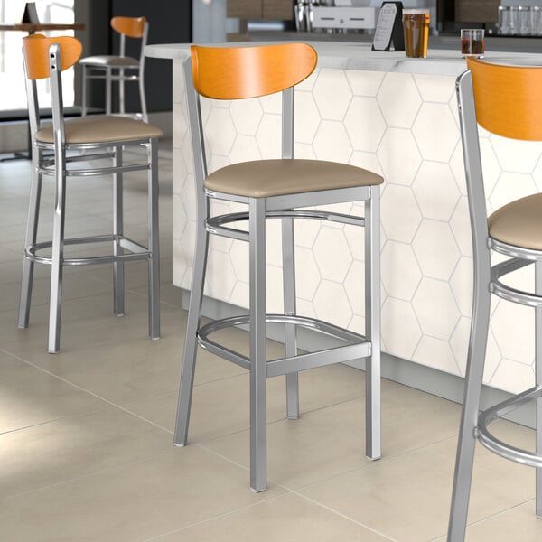 Lancaster Table & Seating Boomerang Series bar stools with taupe vinyl seats and cherry wood backs.