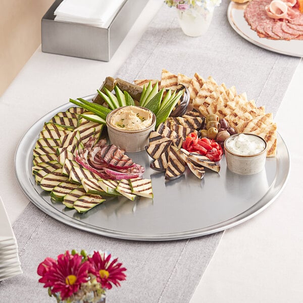 A Choice aluminum round tray with a variety of food on it on a table.