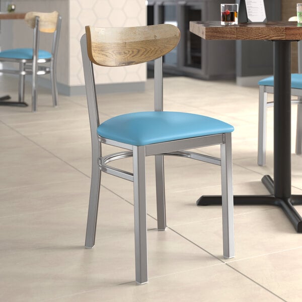 A Lancaster Table & Seating chair with a blue vinyl seat and driftwood back on a table in a restaurant.