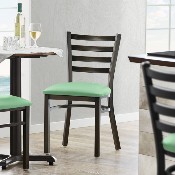 A Lancaster Table & Seating black metal ladder back chair with a 2 1/2" seafoam vinyl padded seat.