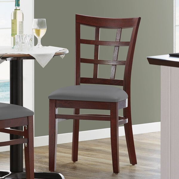 A Lancaster Table & Seating mahogany wood chair with dark gray vinyl seat on a table.