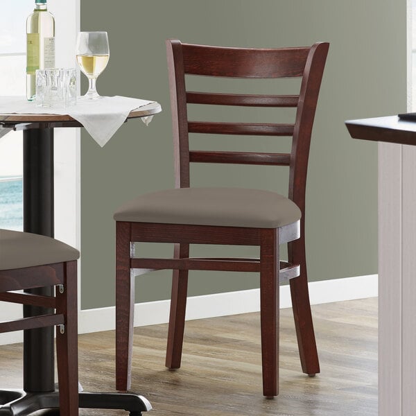 A Lancaster Table & Seating mahogany wood restaurant chair with a taupe vinyl seat.
