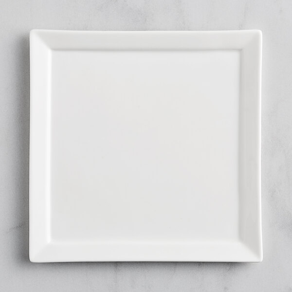 A Fortessa Fortaluxe Tavola bright white square porcelain plate on a gray surface.