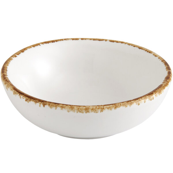 A Fortessa bright white china coupe dip dish with brown speckled edges.
