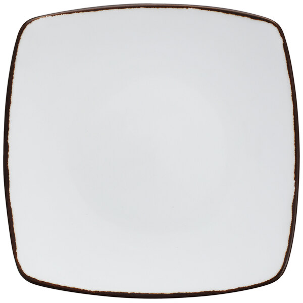 A Fortessa bright white square coupe plate with brown earth hue edges.