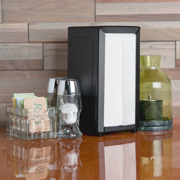 A black Tablecraft tallfold napkin dispenser on a table.
