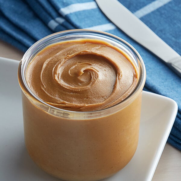 A close-up of a jar of creamy peanut butter on a plate.