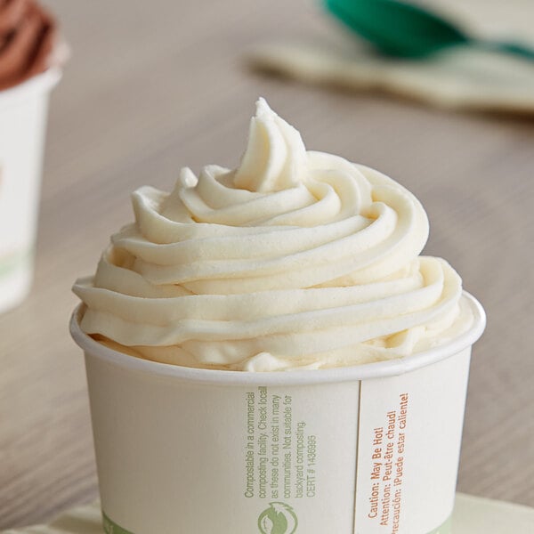 A cup of vanilla soft serve ice cream with white frosting.