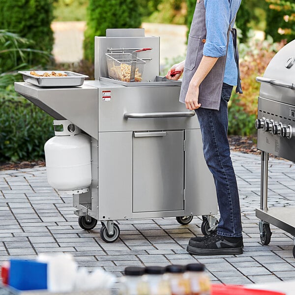 A person standing next to a Backyard Pro fryer on a patio.