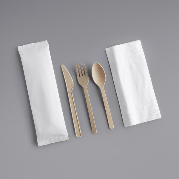 A Greenprint heavy weight natural agave spoon, fork, and knife set with a white napkin on a gray surface.