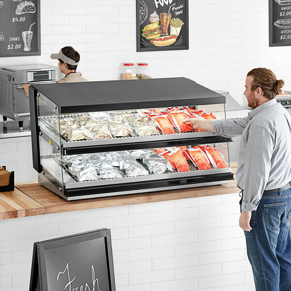 A man putting food in a ServIt countertop heated display case.