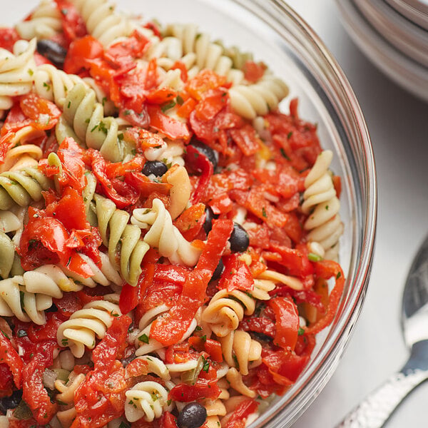 A bowl of pasta salad with Peppadew diced sweet piquante peppers, tomatoes, and olives.