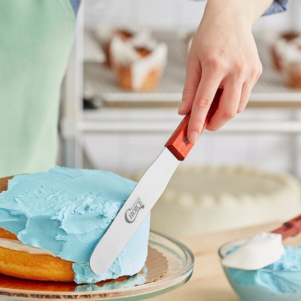 A person using a Choice baking spatula to cut a cake.