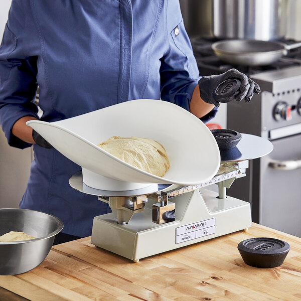 A person weighing dough on an AvaWeigh baker's dough scale.
