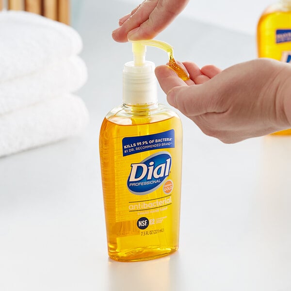 A person pouring Dial Professional Gold liquid hand soap into a hand soap dispenser.