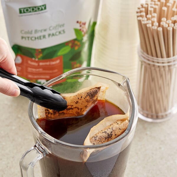 A person pouring Toddy Blend decaf cold brew coffee into a pitcher.