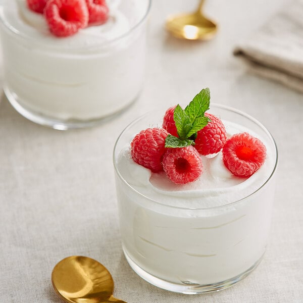 Two glasses of Callebaut white chocolate mousse with raspberries and mint on top.