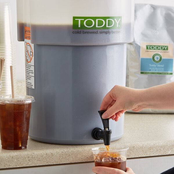 A person pouring Toddy Blend cold brew coffee into a glass.