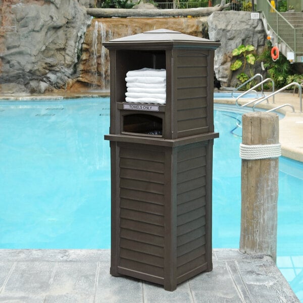 A brown rectangular Mayne Lakeland outdoor storage container with towels on it.