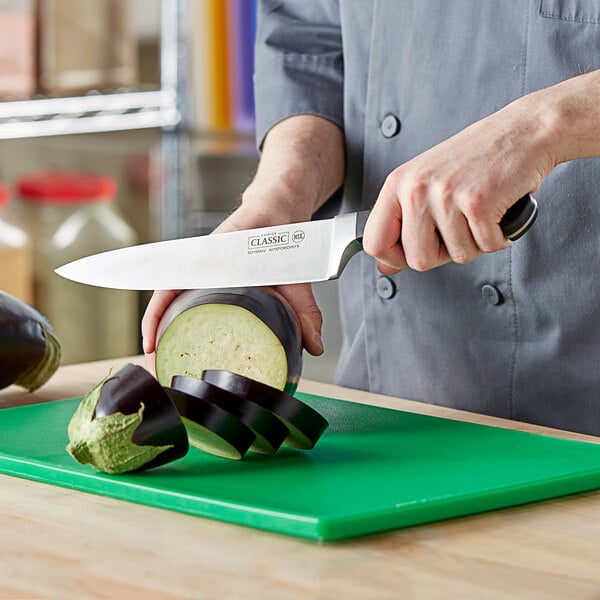 A person using a Choice Classic Chef Knife to cut eggplant on a cutting board.