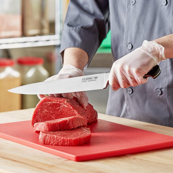 A person using a Choice Classic Chef Knife to cut meat on a cutting board.