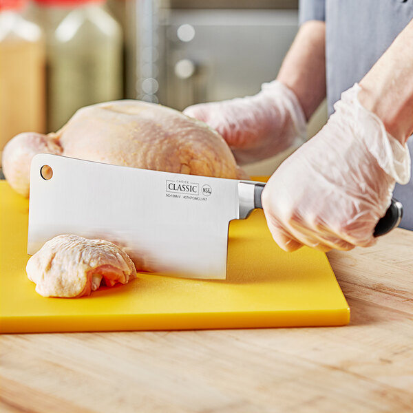 A person using a Choice Classic cleaver to cut meat on a cutting board.