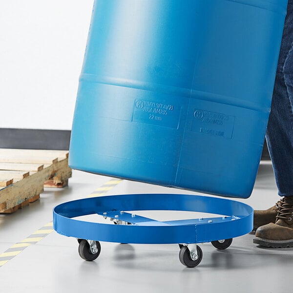 A man using a Lavex steel drum dolly to move a blue drum.